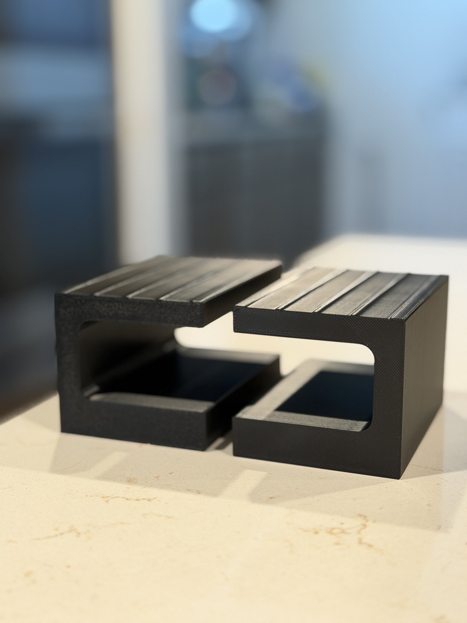 Black PETG under-desk laptop mount printed by Q Fabrication Labs, front view showing the mounting flange and the slot that holds the laptop.